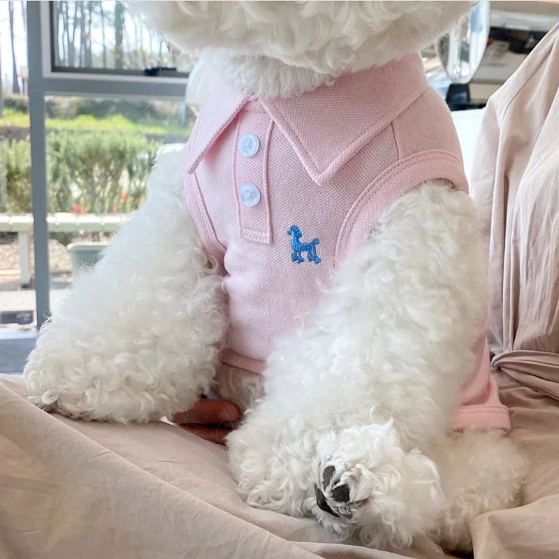 Small white dog wearing a pink sleeveless polo shirt